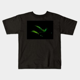 Bright green palm frond caught in sun against black background Kids T-Shirt